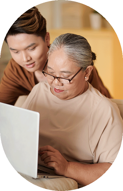 Young man helping senior on computer