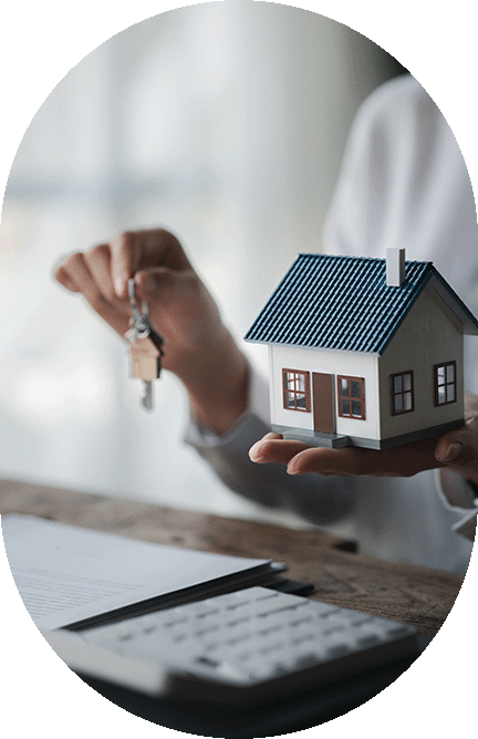 small cardboard house in the palm of a hand with the other hand holding a set of keys