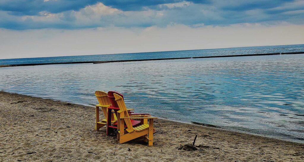 2 beach chairs on the sand looking out to the water