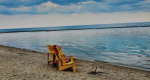 2 beach chairs on the sand looking out to the water